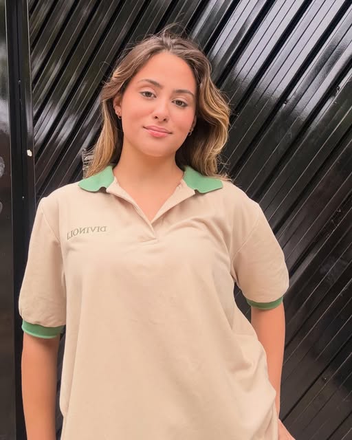 Modelo vestindo uniforme polo bege com gola verde da Brunecomodas