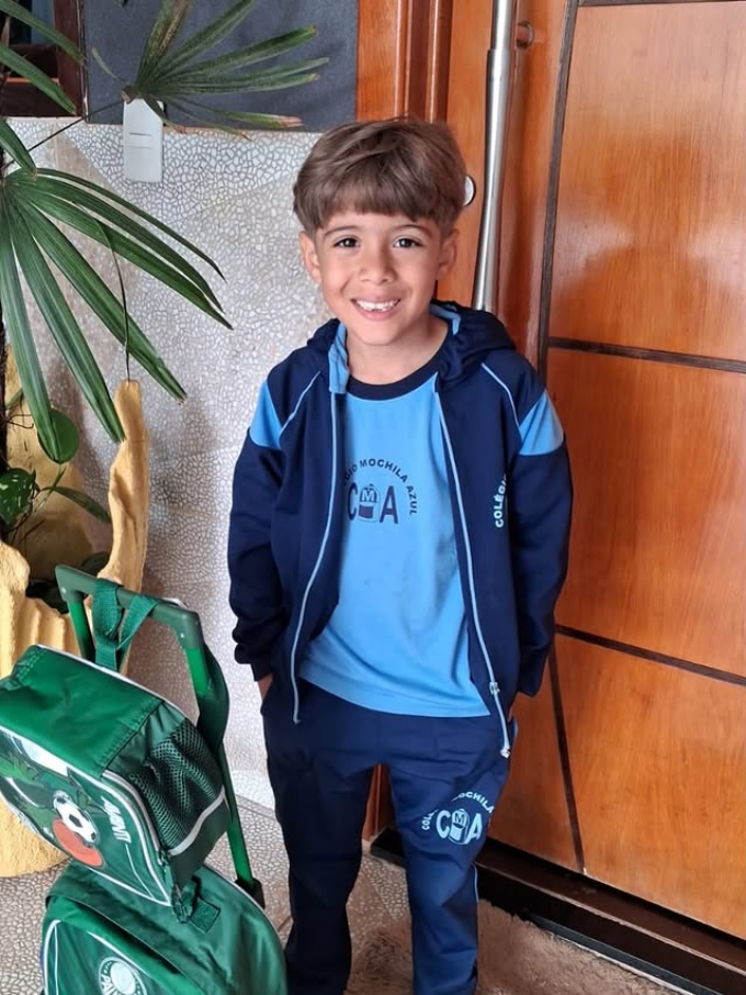 Criança vestindo conjunto escolar azul com camiseta, agasalho e calça